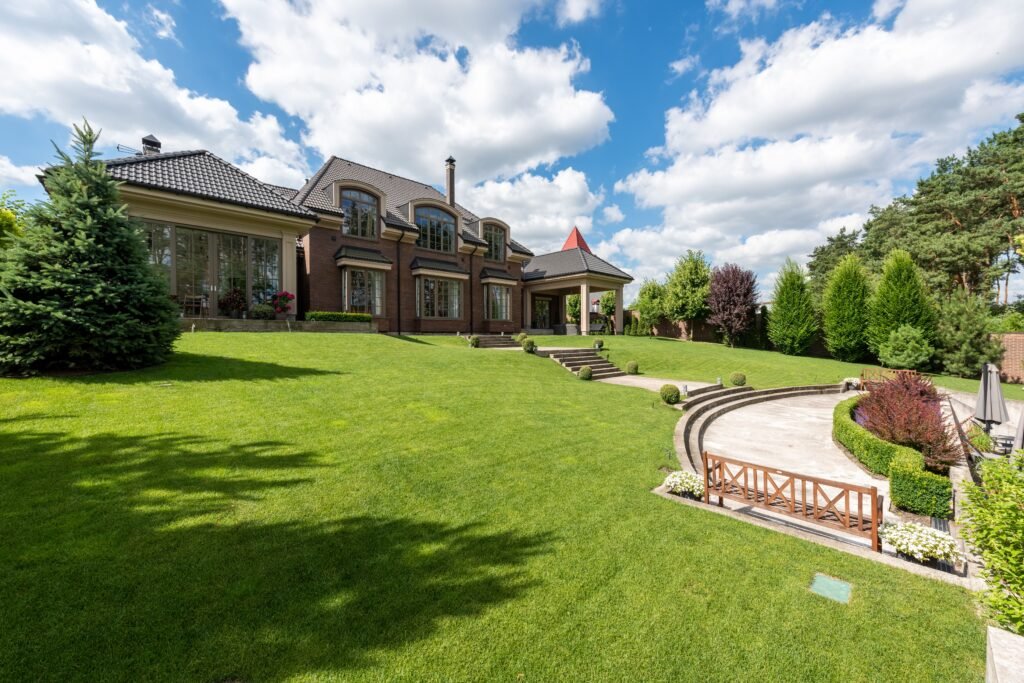 Why Abuja Remains One of Nigeria's Best Real Estate Investment Destinations Elegant brick mansion with manicured lawn and garden under a bright blue sky.